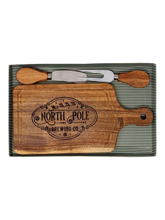 Hand-burned North Pole Brewing Co. cheeseboard with wood-handled cheese knife and fork in a green striped gift box